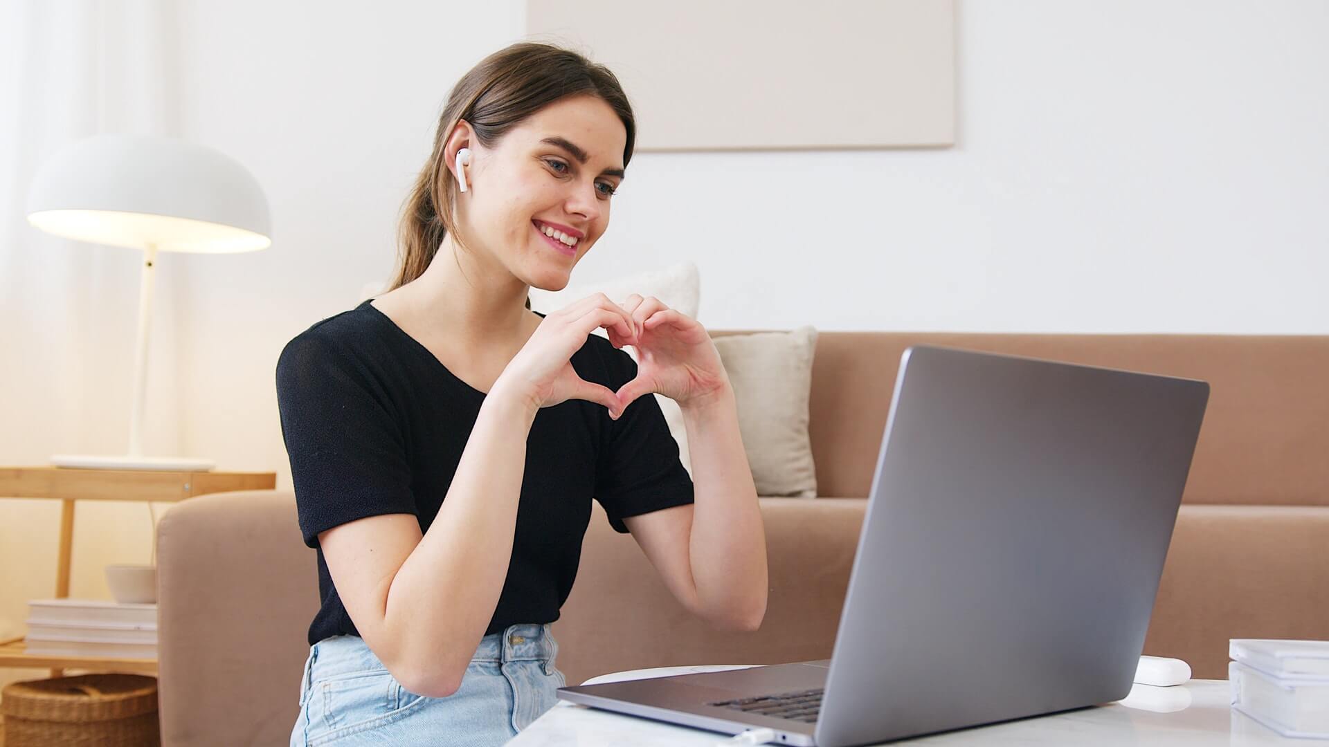 Woman making heart shape with her hands during live chat.