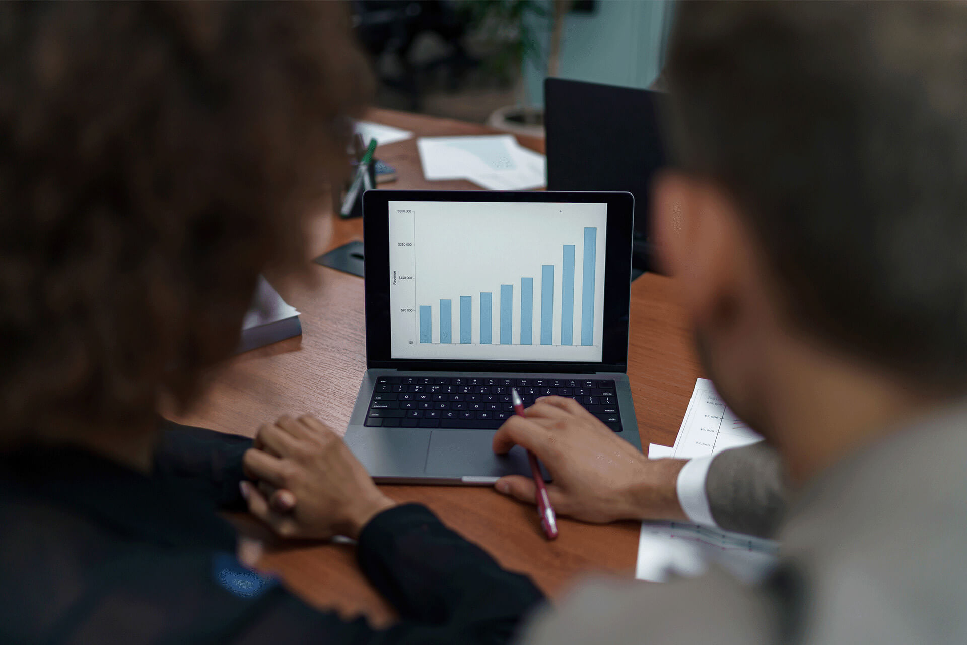 Workers looking at bar chart on laptop Workers looking at bar chart on laptop